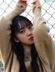 A woman standing in front of a chain link fence.