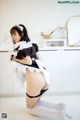 A woman in a maid outfit is posing for the camera.