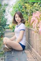 A woman sitting on a wooden bench in a garden.