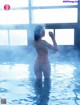 A naked woman standing in a pool of water.