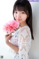 A woman holding a bunch of pink flowers in her hand.