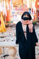 A woman wearing a black coat and a pink scarf.
