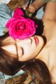 A woman laying on a bed with a pink rose in her hair.