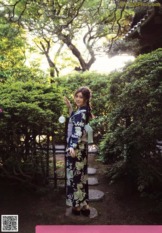 A woman in a kimono standing in a garden.