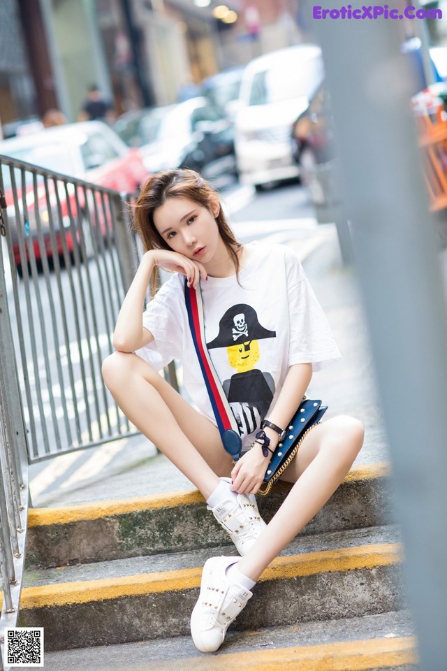 A woman sitting on the steps of a city street.
