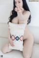 A naked woman sitting on a white couch blowing a kiss.