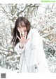 A woman in a white coat standing in the snow.